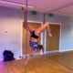 Upside down and elevated women on a pole dancing pole holding on with two hands and her right leg upside down.